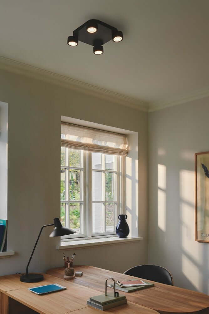 LED Deckenleuchte Clyde 4-Spot in einem modernen Raum mit Holzschreibtisch und Fenster.