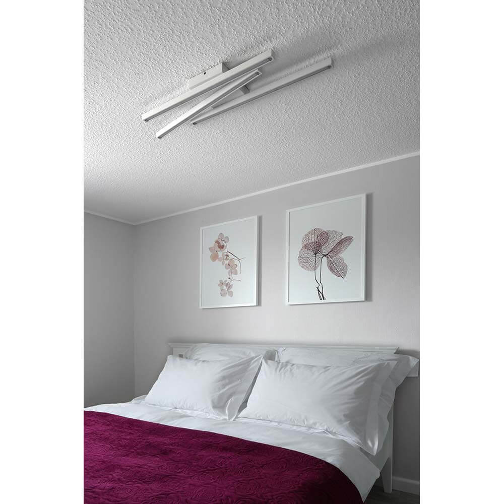 LED Deckenleuchte Linus Sidelong 2520lm Weiß über einem Bett mit weißen Bettlaken und dekorativen Bildern an der Wand.