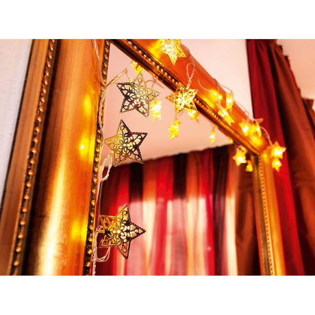 LED Decorative string lights gold-colored metal stars 16 warm white diodes on a mirror, glowing in warm light.