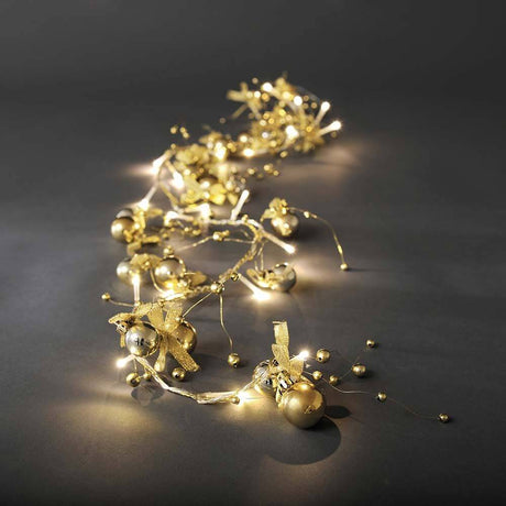 LED Dekolichterkette goldfarbene Perlen und Schleifen 20 Warmweiße Dioden auf dunklem Hintergrund