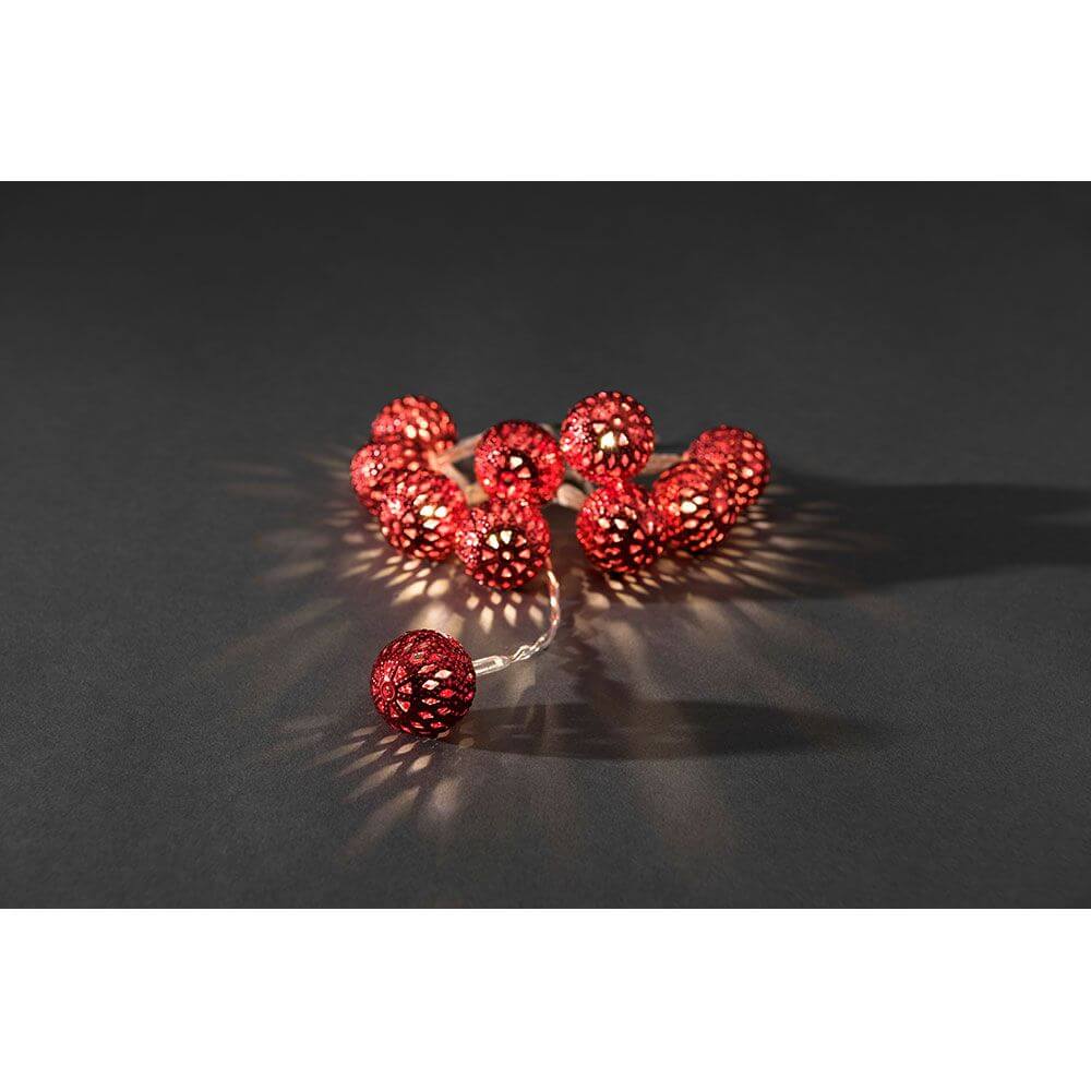 LED Dekolichterkette kleine rote Metallbälle 10 Warmweiße Dioden batteriebetrieben auf dunklem Hintergrund.