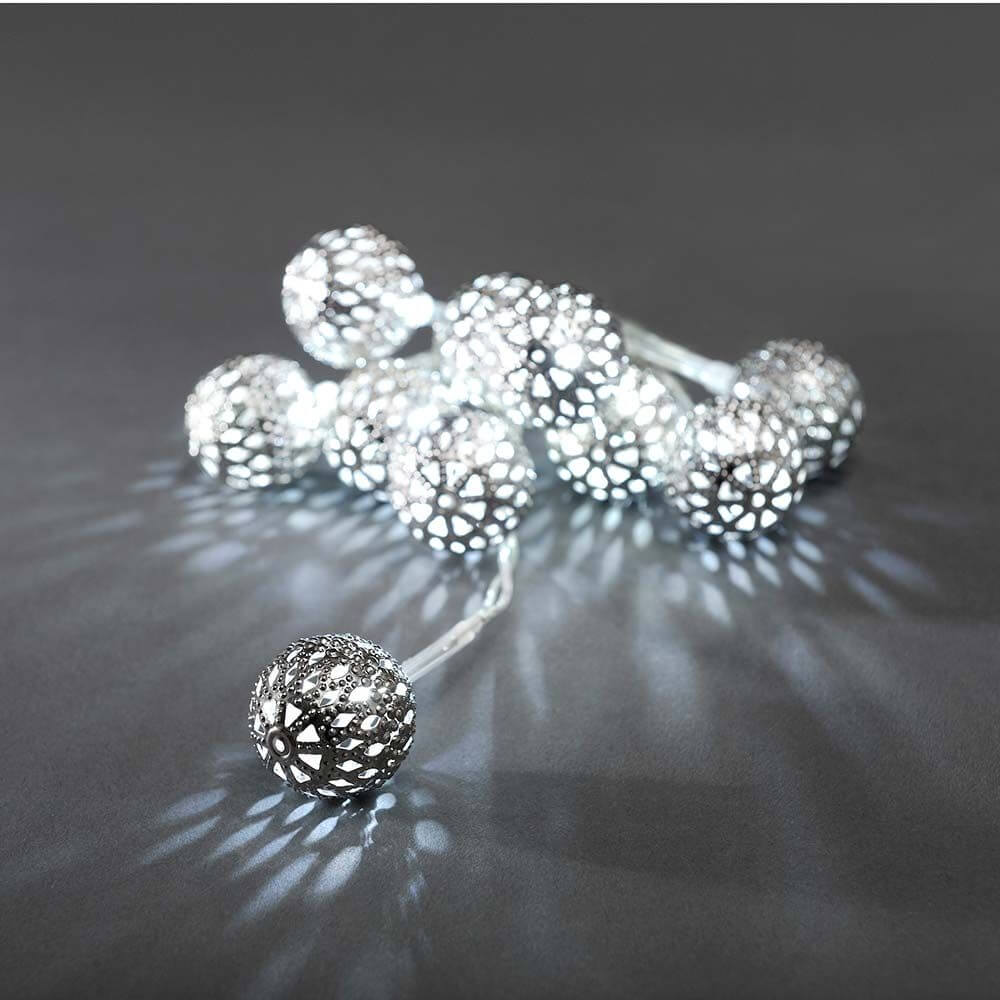 LED Dekolichterkette kleine silberfarbene Metallbälle 10 Kaltweiße Dioden batteriebetrieben auf dunklem Hintergrund.