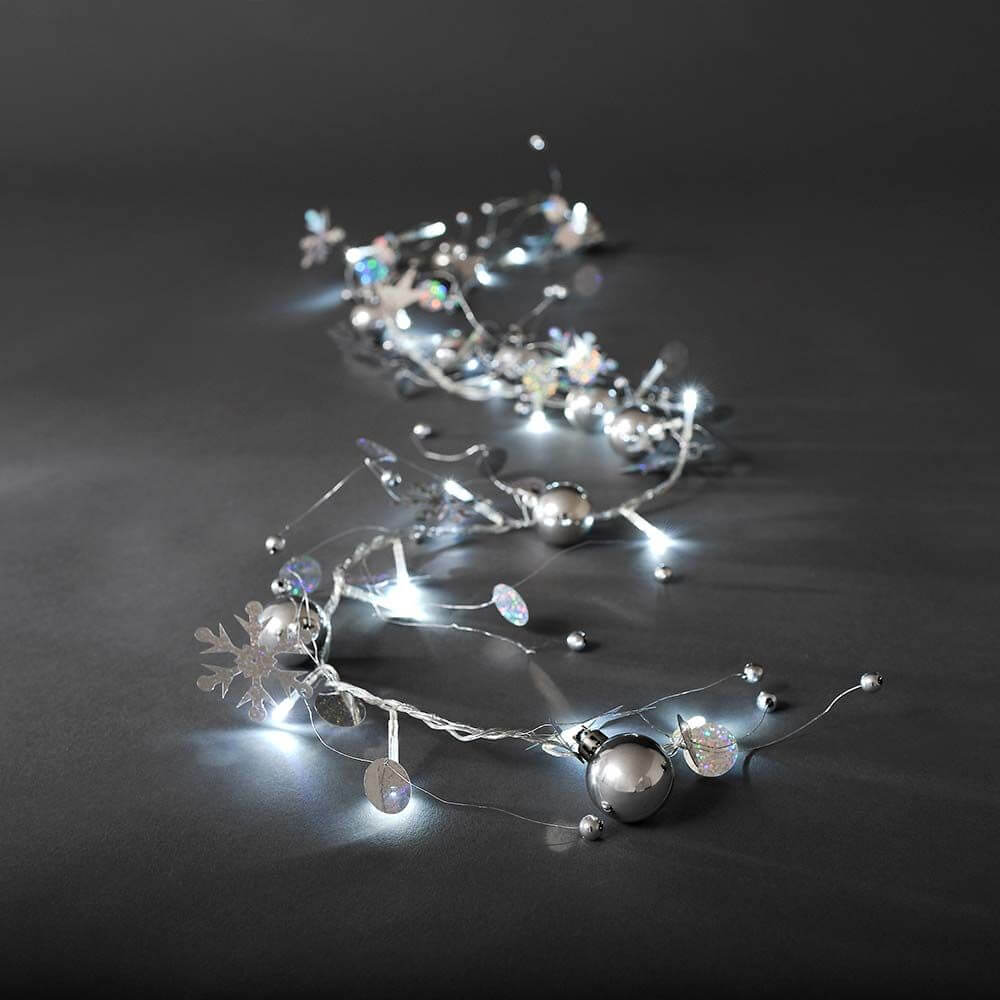 LED Dekolichterkette silberfarbene Perlen und Schneekristalle 20 Kaltweiße Dioden auf einem dunklen Hintergrund