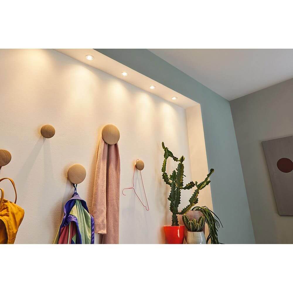 Moderne Wand mit Holz-Haken und LED-Beleuchtung, dekoriert mit Farbtextilien und Pflanzen.