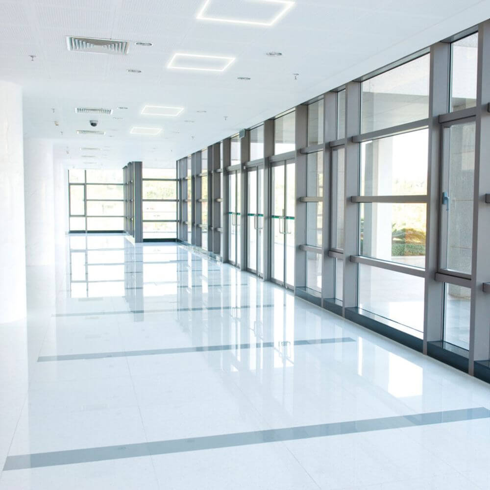 Heller Flur mit modernen LED-Panels und glasigen Wänden, ideal für Büroanlagen