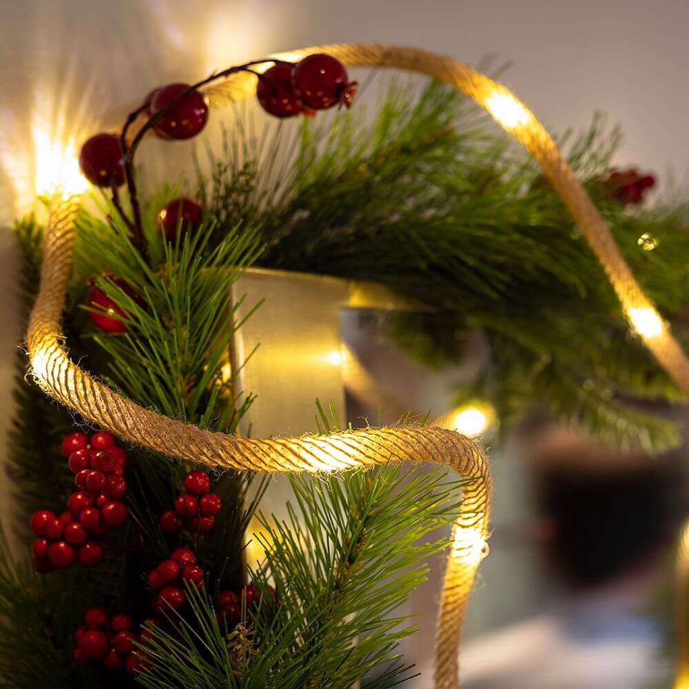 LED Jute-Lichterkette Lia IP44 dekorativ um Pflanzen gewickelt, ideal für Weihnachtsdekoration.