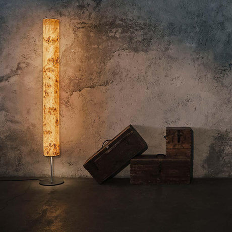 LED gulvlampe i tre Arbor 190 cm poppelmaser ved siden av trekister foran en rå vegg.