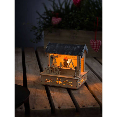 LED Holzsilhouette naturfarben Marktstand mit grauem Dach 3 Warmweiße Dioden batteriebetrieben auf Holzuntergrund.