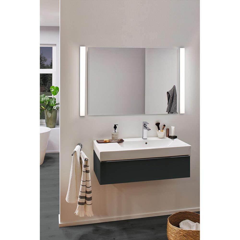 LED HomeSpa Spiegelleuchte Tova Dim-to-Warm Chrom, Weiß neben einem modernen Badezimmer-Spiegel und Waschbecken.