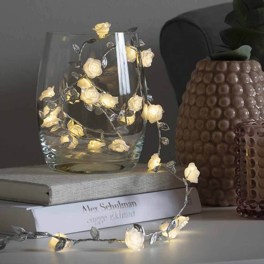 LED Lichterkette mit Dekoblättern 6h Timer batteriebetrieben, dekorativ in einem Glas mit blühenden Rosen.