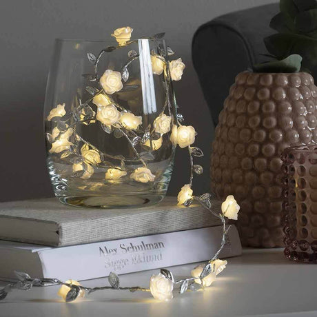 LED Lichterkette mit Dekoblättern 6h Timer batteriebetrieben, dekorativ in einem Glas mit blühenden Rosen.