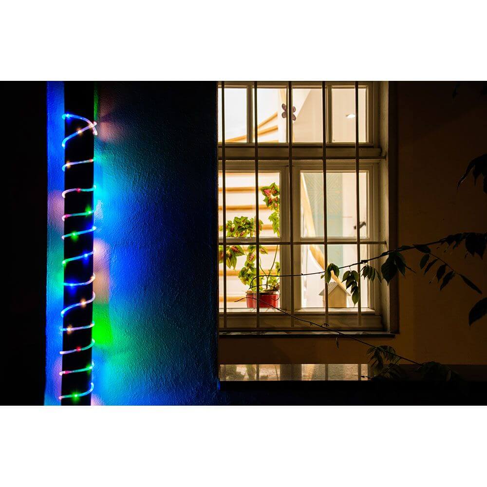 LED Mini Lichterschlauch 10m mit Lichtsensor Timer 130 bunte Dioden batteriebetrieben IP44 an einem Fenster in der Nacht.