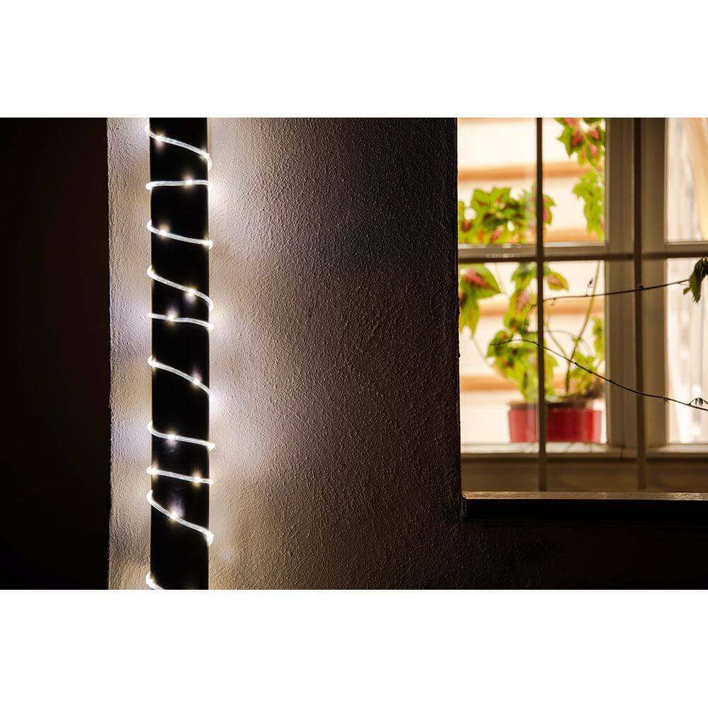 LED Mini Lichterschlauch 10m mit Lichtsensor Timer 130 Warmweiße Dioden batteriebetrieben IP44 um ein Fenster dekoriert.