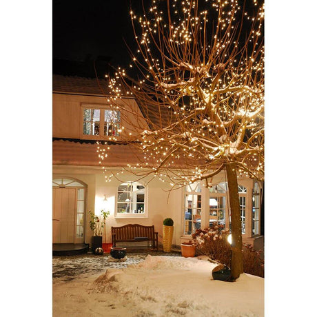Beleuchteter Baum mit LED Minilichterkette 304 Warmweiße Dioden IP44 in verschneitem Garten bei Nacht.