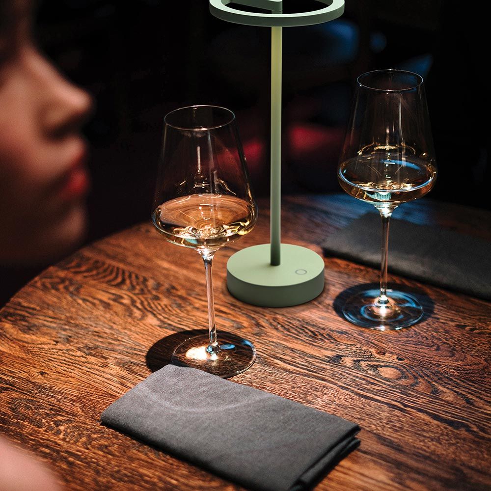 Stimmungsvolle LED Akku-Tischlampe "Smart" auf einem Restauranttisch mit Weingläsern und Stoffservietten.