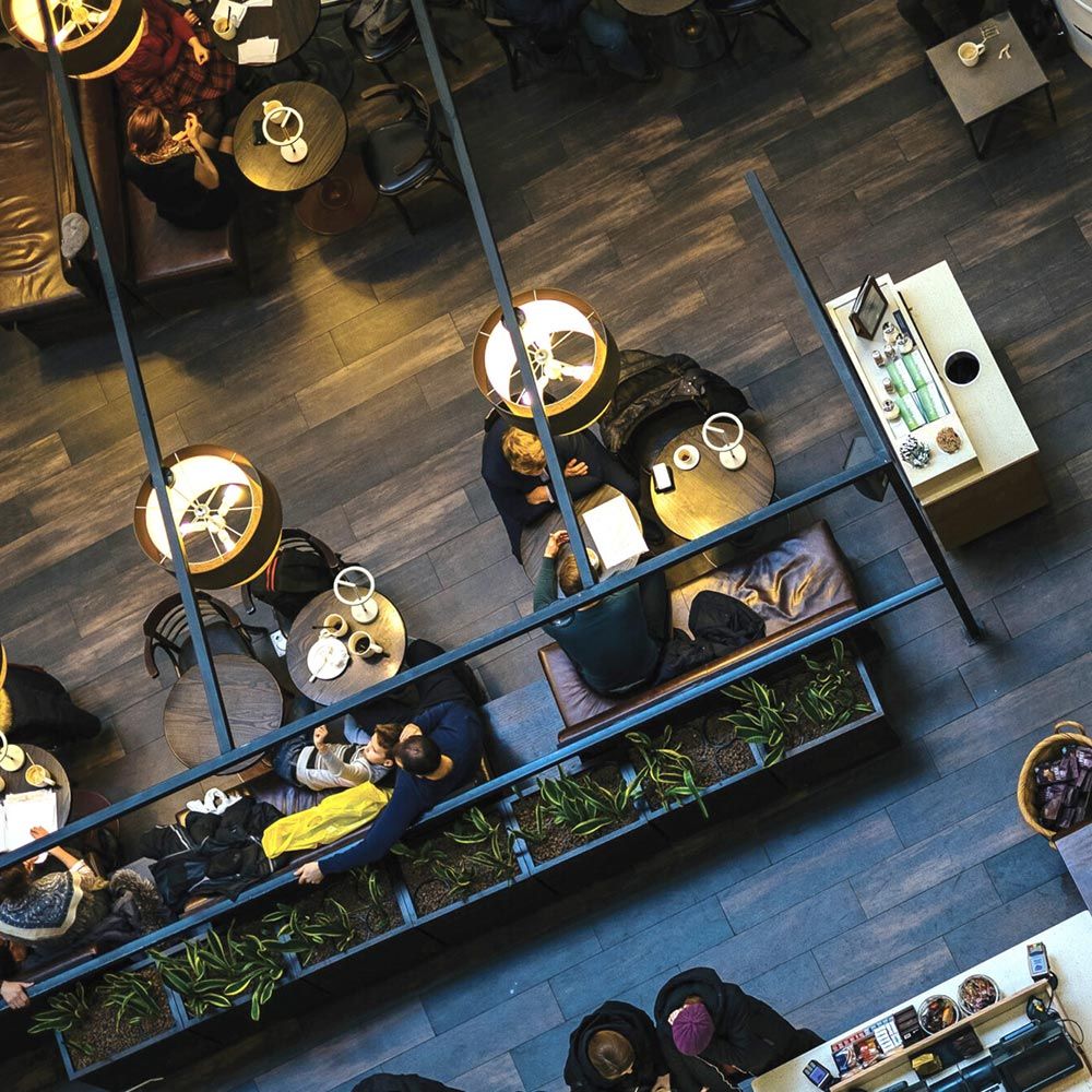 Luftaufnahme eines modernen Cafés mit stilvollen Tischen und LED-Tischlampen, die eine einladende Atmosphäre schaffen.