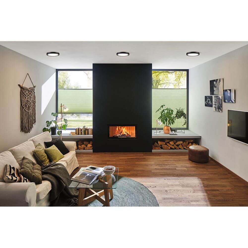 LED Panel Abia Rund Schwarz-Matt in modernem Wohnzimmer mit Kamin und gemütlicher Einrichtung.