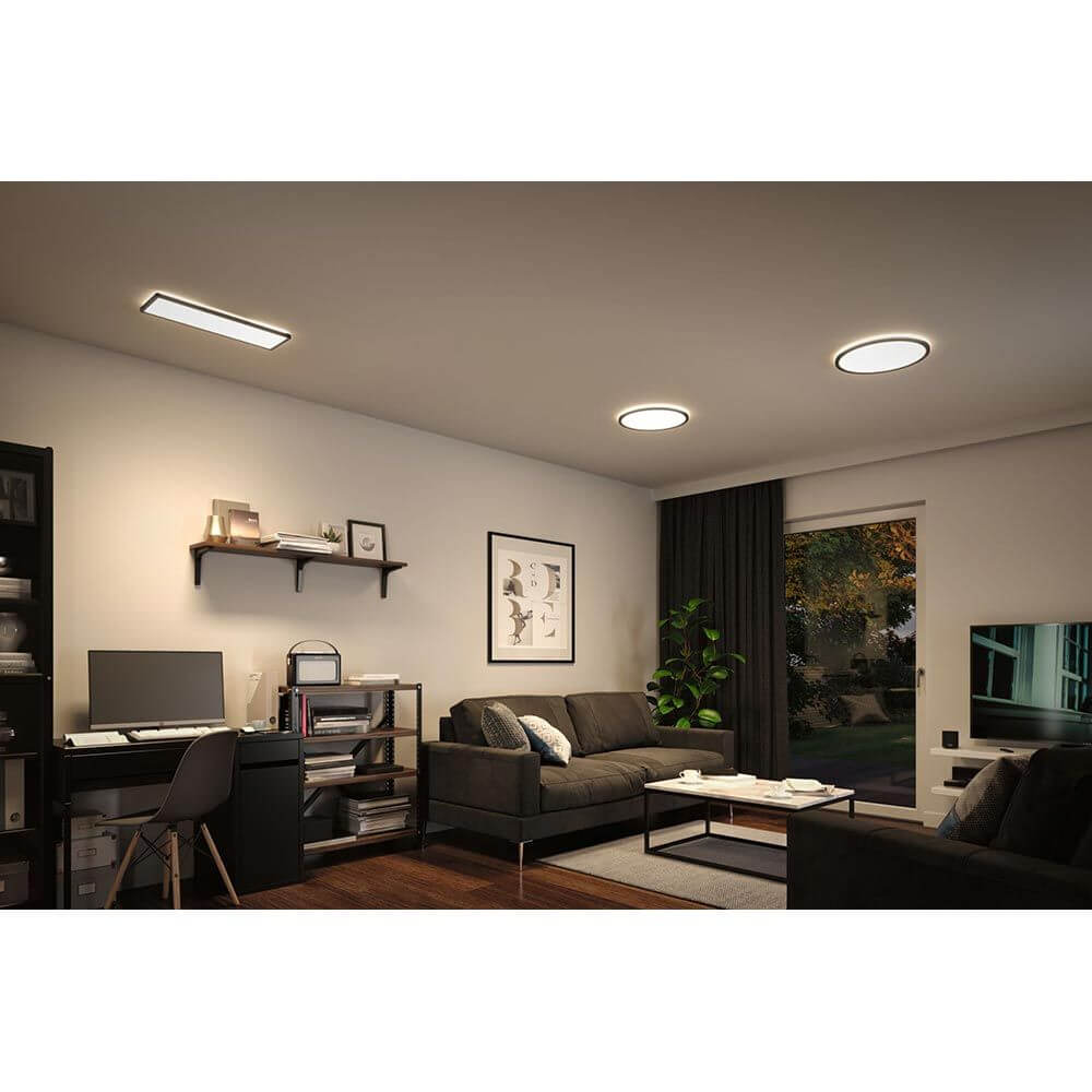 Gemütliches Wohnzimmer mit LED Deckenpanel Atria Shine in schwarz, warmweißer Beleuchtung und moderner Einrichtung.