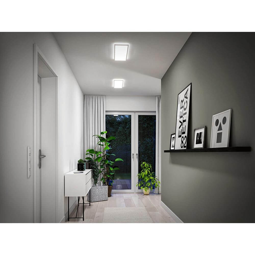 LED Panel Atria Shine Wärme-Dimmbar Weiß in einem modernen Flur mit Pflanzen und stilvollen Dekorationsobjekten.