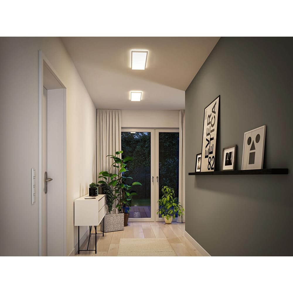LED Panel Atria Shine Panel Eckig Weiß im modernen Flur mit Pflanzen und kunstvollen Wanddekorationen.
