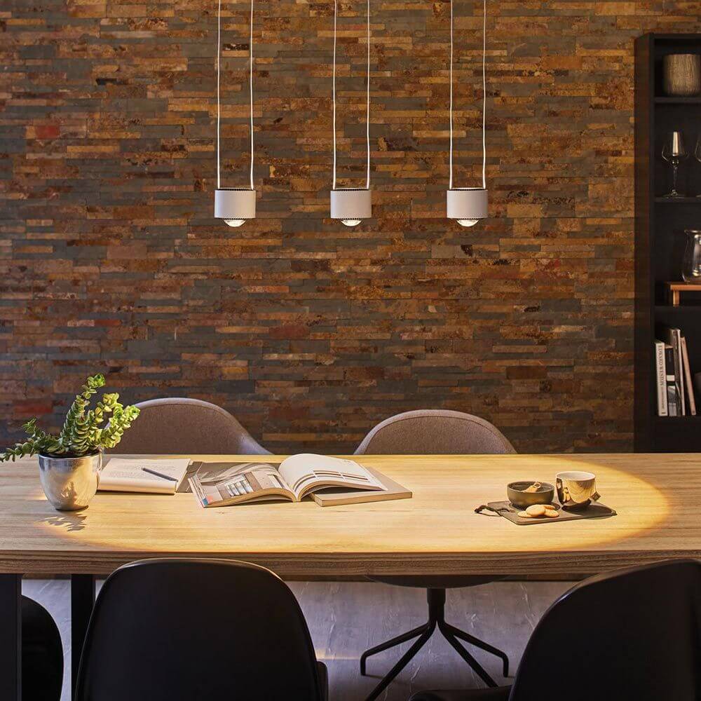 LED Pendelleuchte Aldan 3-flammig 3x9W über einem modernen Esstisch mit Holzplatte.
