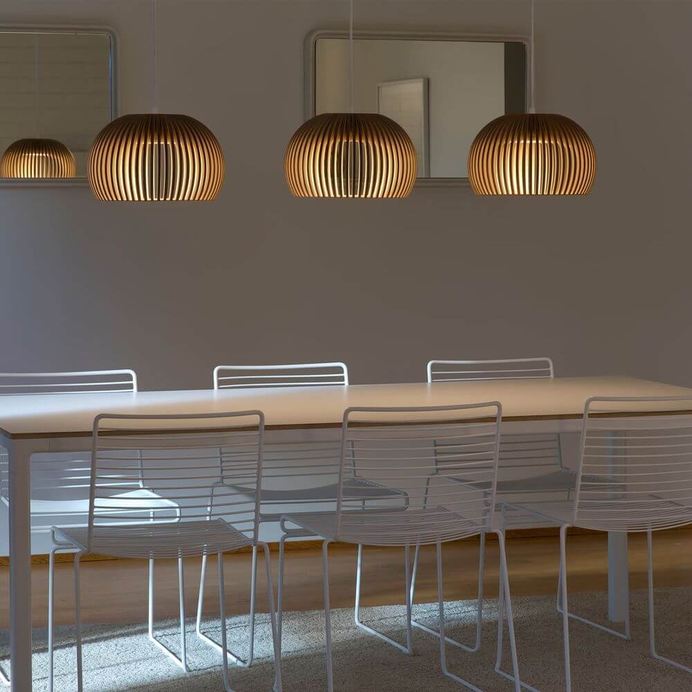 LED Pendelleuchte Atto 5000 aus Holz Ø 34cm über einem weißen Esstisch mit modernen Stühlen.