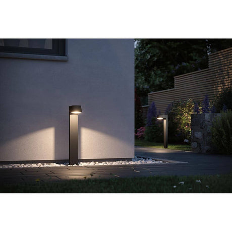 LED Bollard luminaire Capea anthracite aluminium illuminates garden path and driveway at night.