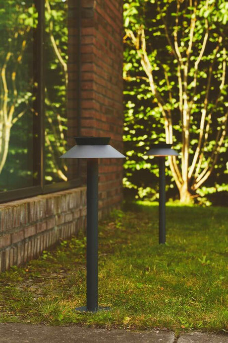 LED Pollerleuchte Justina Solar IP44 im Garten, perfekt zur Beleuchtung von Einfahrt und Wegen.