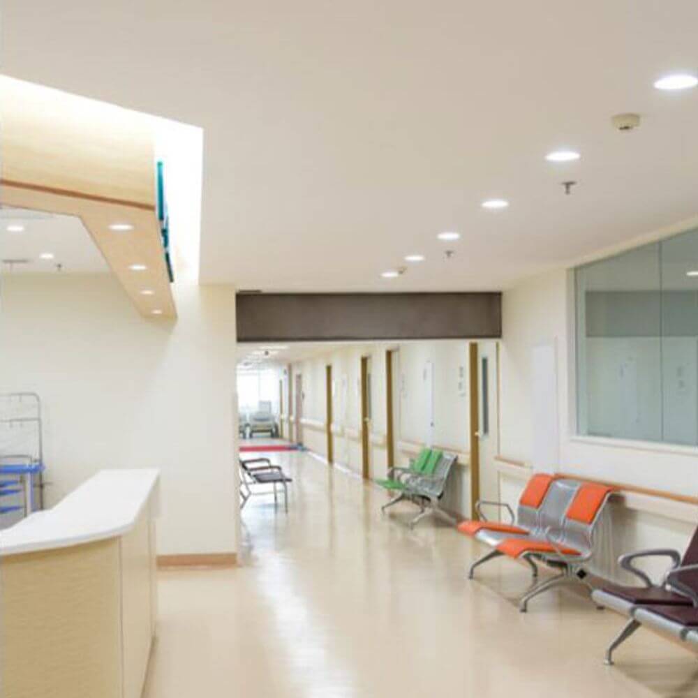 Helle, moderne Krankenhausflur mit LED-Downlights und Wartebereich mit Stühlen.