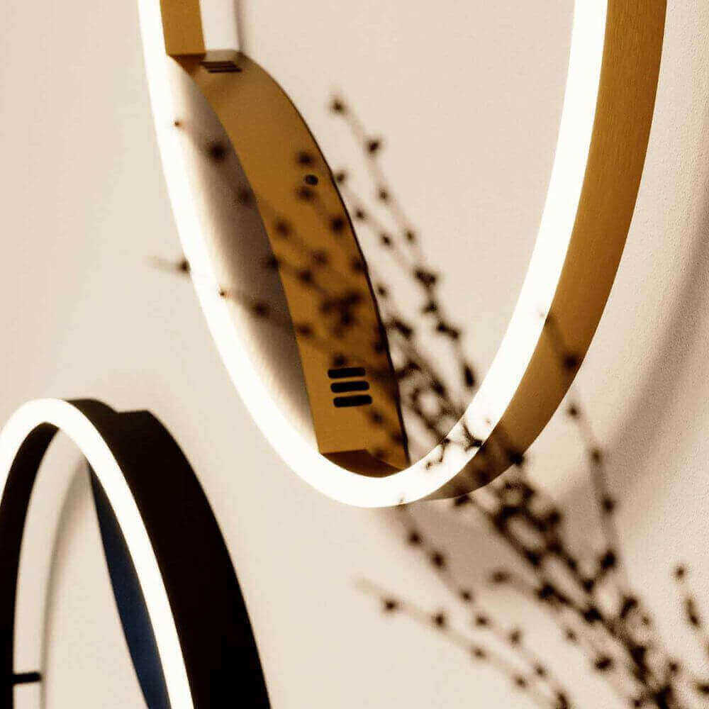 Modern runde Wandlampen in Gold und Schwarz mit Schattenwurf auf einer neutralen Wand.