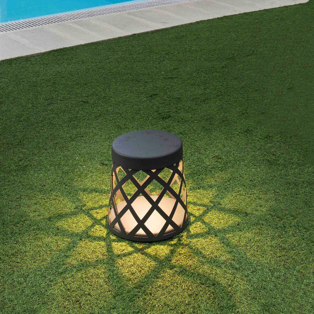 LED Sockellampe SHADOW IP65 Dunkelgrau auf grünem Rasen neben einem Pool, mit warmem Licht.