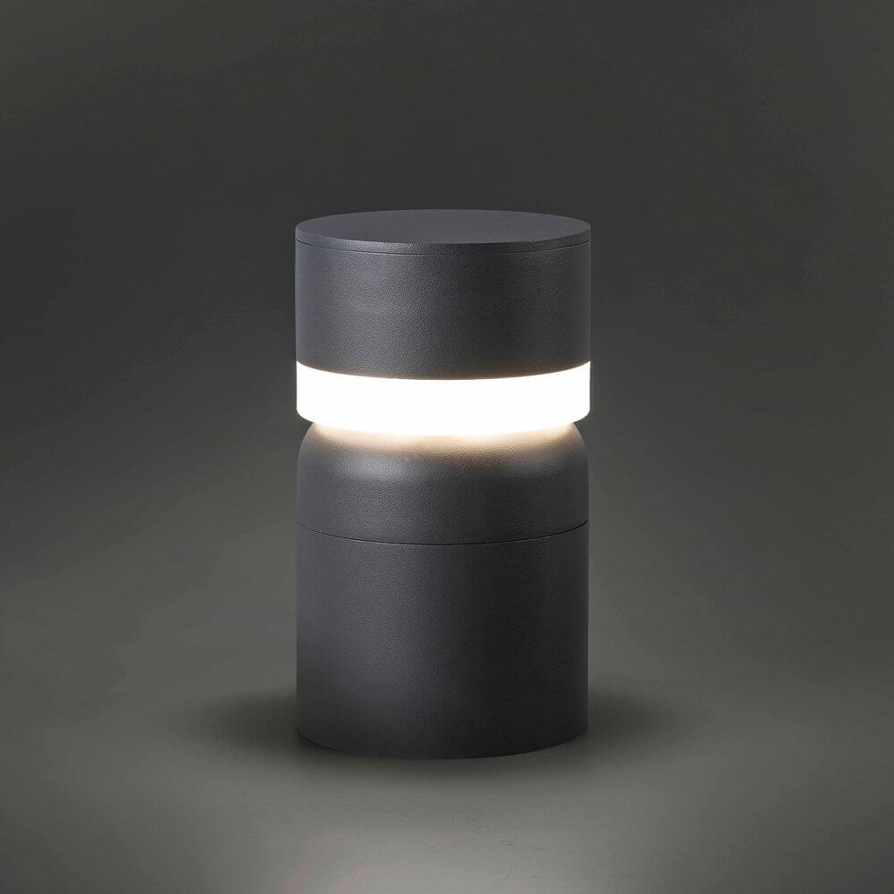 LED Sockelleuchte SETE 6W 3000K 25cm IP54 Dunkelgrau auf einem dunklen Hintergrund.