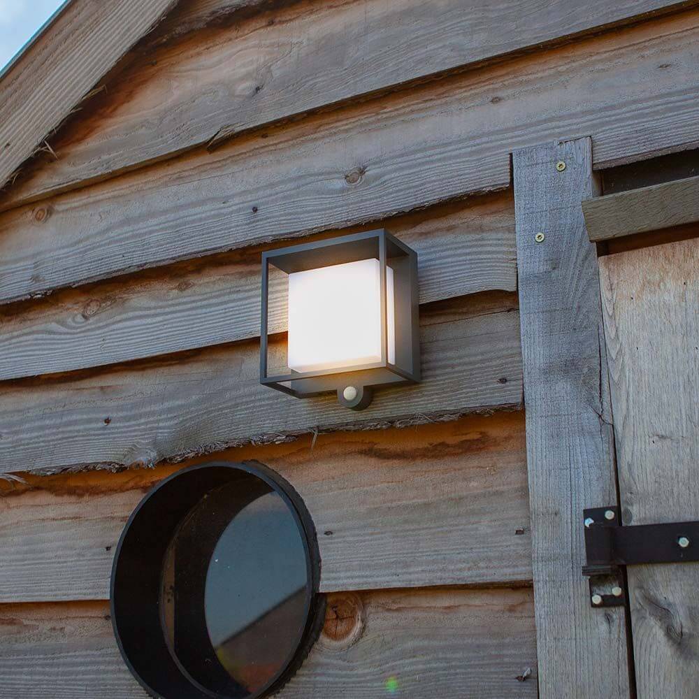 LED-Solar-Außenleuchte Curtis mit Bewegungsmelder an einer Holzwand montiert.