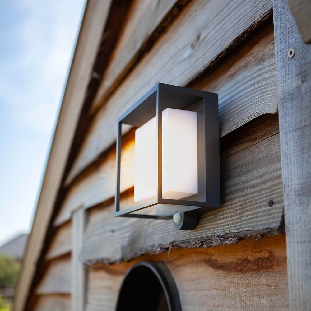 LED-Solar-Außenleuchte Curtis mit Bewegungsmelder an einer Holzfassade.