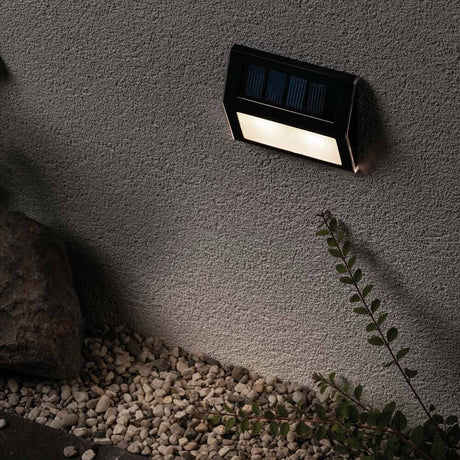 LED Solar step wall & stair light IP44 3000K anthracite mounted on a wall, surrounded by stones.