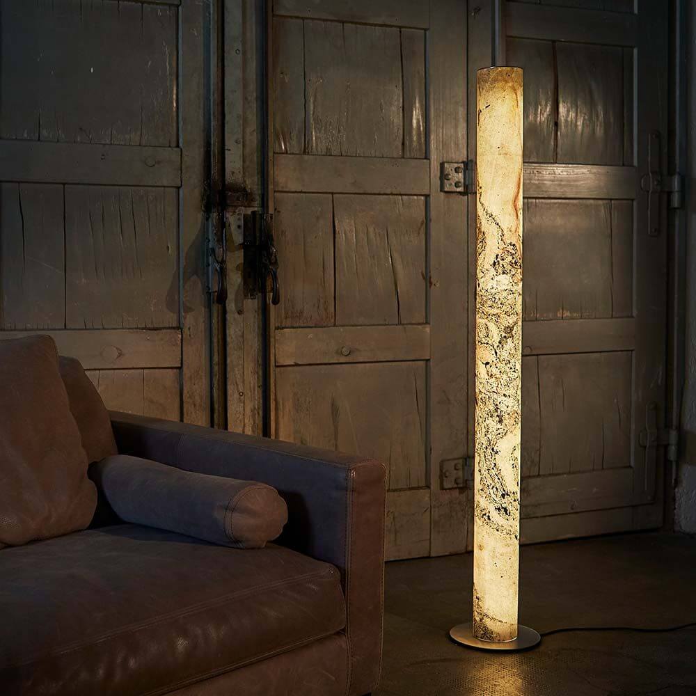 LED Stehleuchte Columna aus Stein Weißperle neben einem Sofa in einem industriellen Raum.