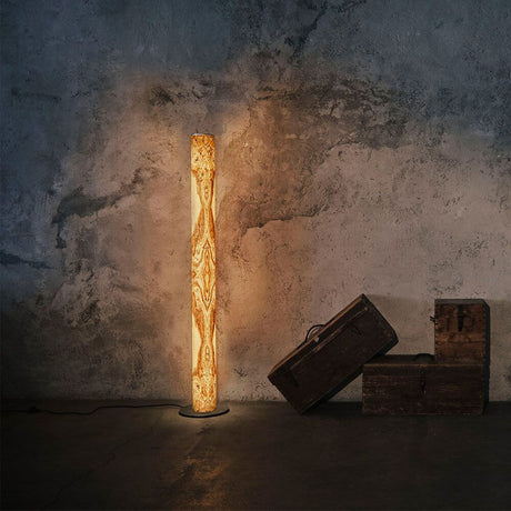 LED-gulvlampe Stein Columna 160 cm Olivmarmorert i et stilfullt rom med trekasser.