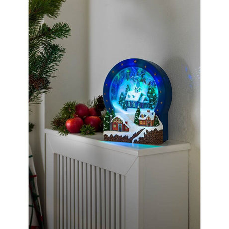 LED Dorf Glas mit Animation Weihnachtsliedern 9 bunte Dioden batteriebetrieben auf einem Heizkörper mit Weihnachtsdekoration.