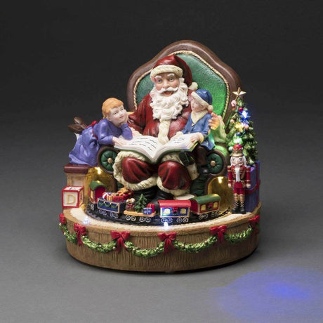 LED Santa Claus with children and train Christmas carols battery-operated indoors on a festive base.