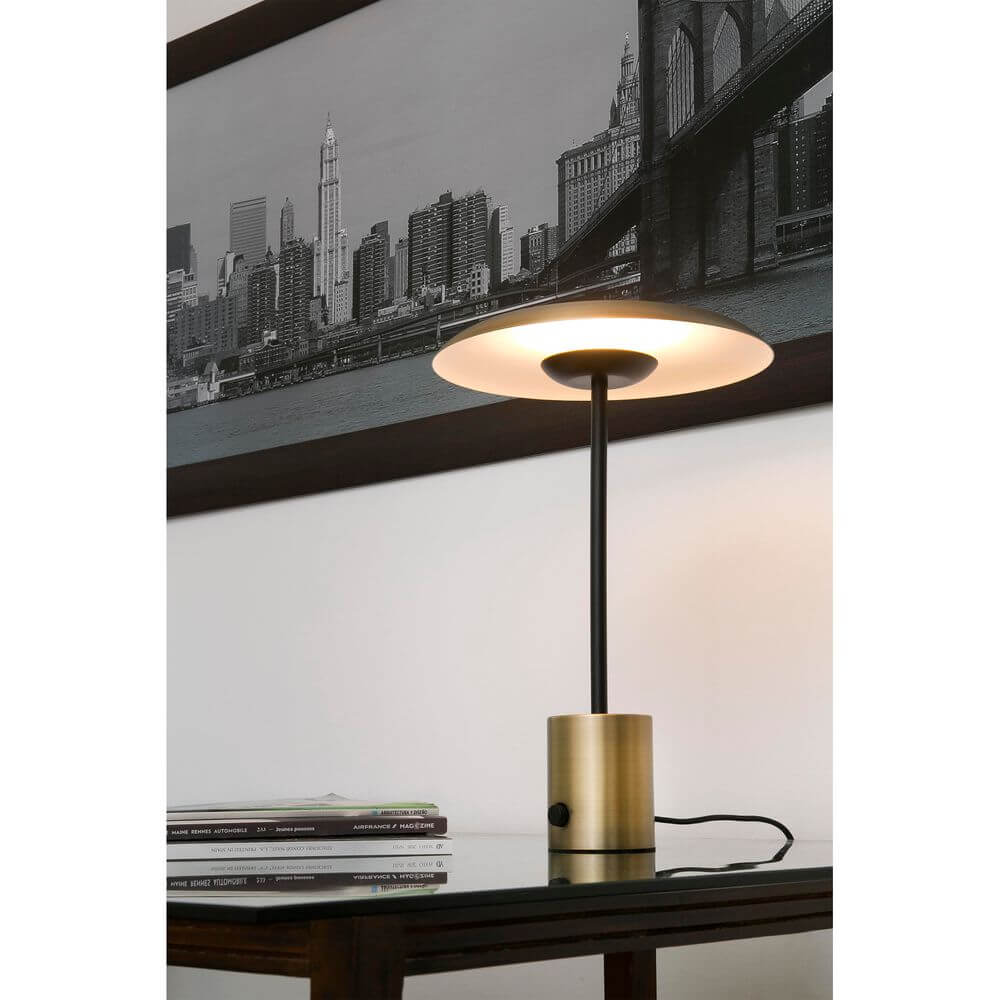 LED Tischlampe HOSHI Goldfarben-Satin, Schwarz auf einem Tisch mit urbanem Hintergrund