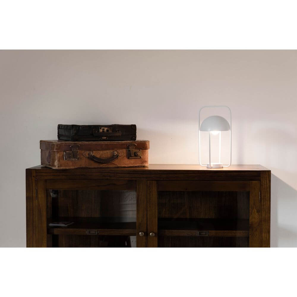 LED Tischlampe JELLYFISH 3W 2700K Weiß auf einem Holzschrank neben alten Koffern platziert.