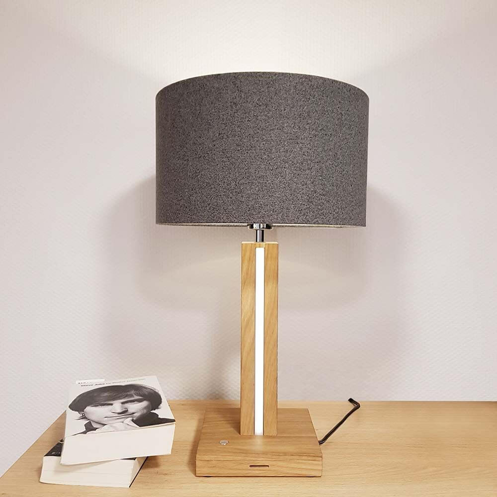 LED Tischleuchte Asseto 980lm Eiche-Geölt, Grau auf einem Holztisch mit Bücher daneben.