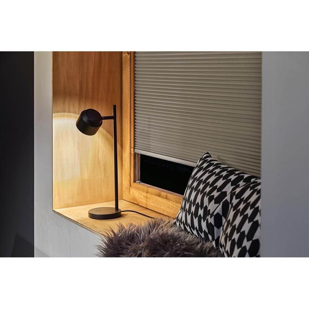 LED Tischleuchte Puric Pane Touch-Dimmer Schwarz auf einem Fensterbrett mit Kissen.