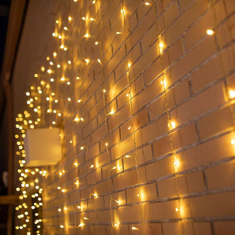 LED Vorhang-Lichterkette Luceo IP44 in warmem Licht an einer Ziegelwand, gemütliche Hintergrundbeleuchtung.