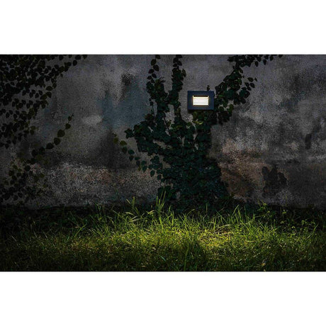 LED Applique encastrée murale SPARK-2 3000K IP65 gris foncé sur un mur avec des plantes.