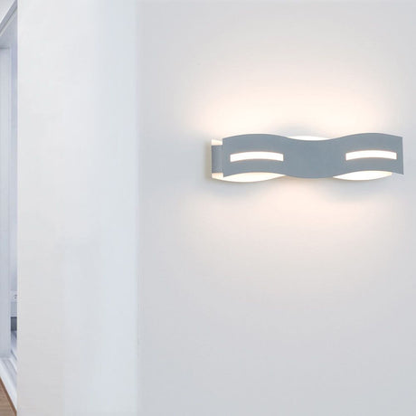 LED Wandlampe Wave Nickel-Matt, Chrom an einer Wand montiert, strahlt warmweißes Licht aus.