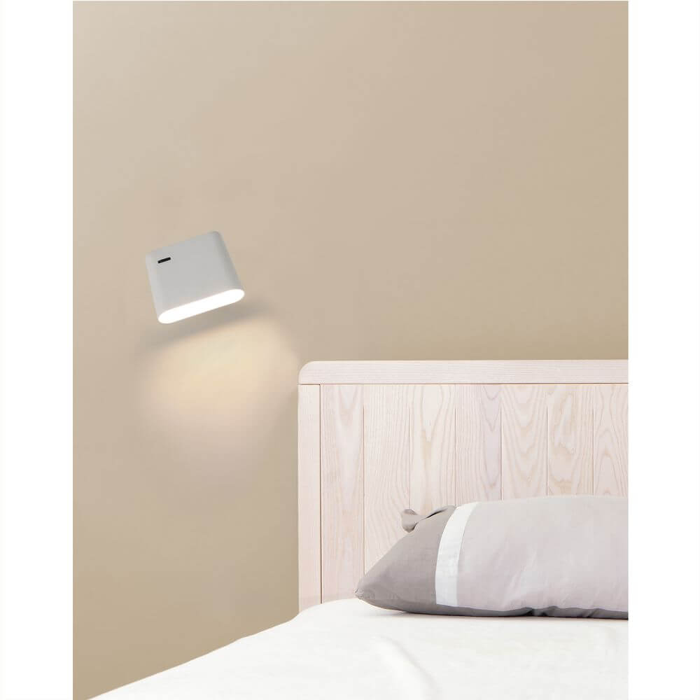LED Wandleuchte AUREA 6W 2700K Weiß an einer Wand über einem Bett.