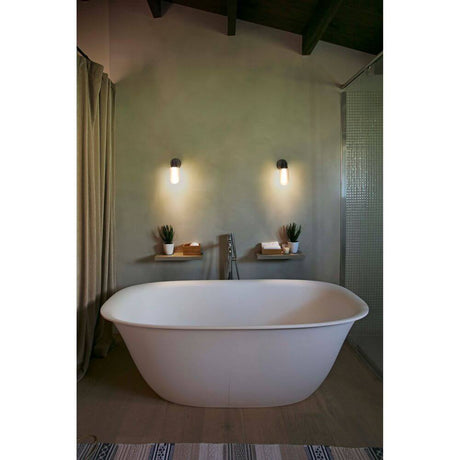 LED Wandleuchte BRUME 3W 2700K IP44 Bronze beleuchtet ein modernes Badezimmer mit freistehender Badewanne.