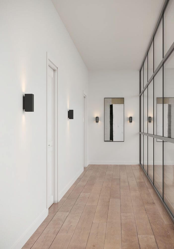 LED Wandleuchte Curtiz in modernem Flur mit Holzfußboden und Spiegelwand.