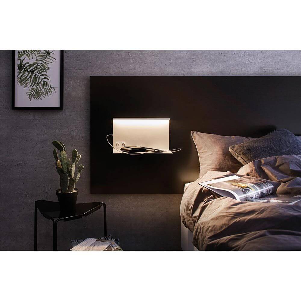 LED Wandlampe Jarina mit Ablage + USB Dimmbar an einem Schlafzimmerbett mit Pflanzen und Zeitschriften.
